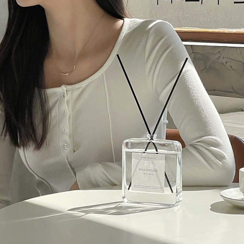 Plant-Inspired Indoor Bedroom Fragrance displayed on a table with a woman elegantly seated nearby.